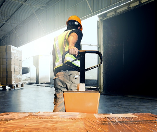 Warehouse worker unloading pallet shipment goods into a truck container, warehouse industry freight, logistics and transport.