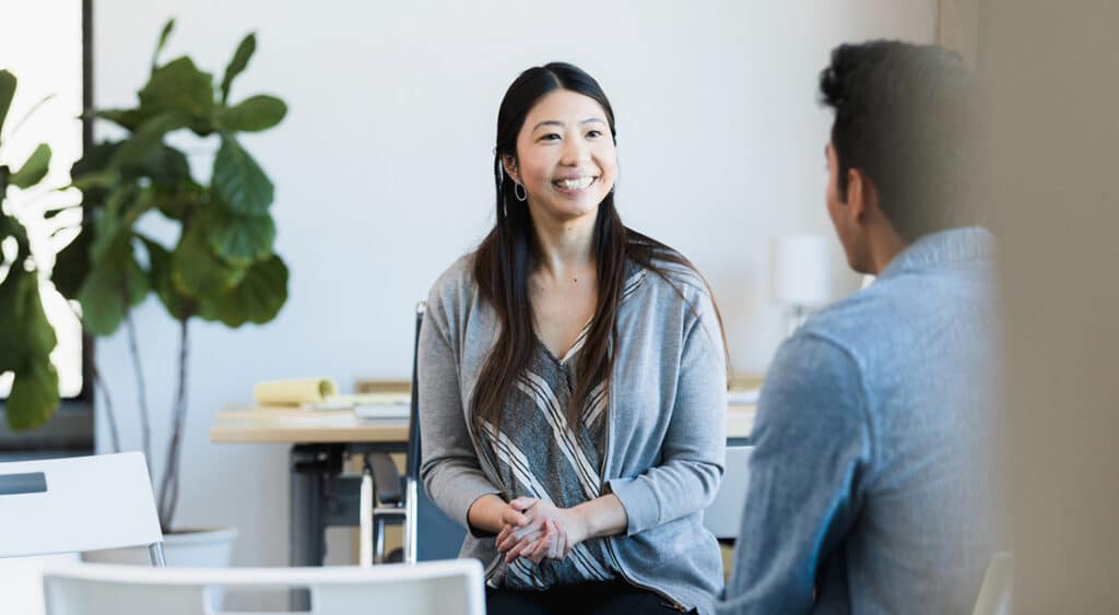 Two professionals facing each other smiling